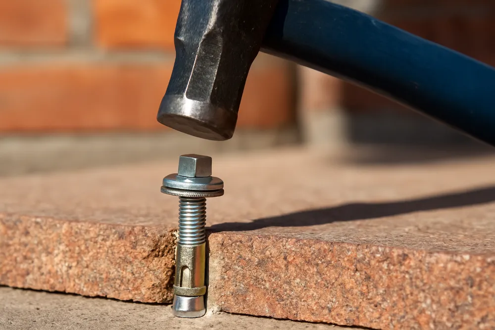 Металевий анкерний болт у процесі встановлення в отвір бетонної основи